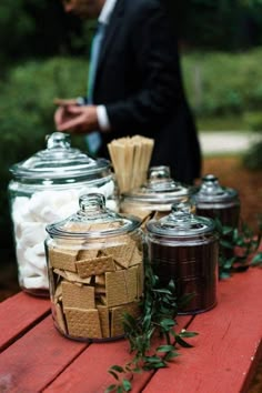 a man in a suit and tie standing next to jars filled with marshmallows