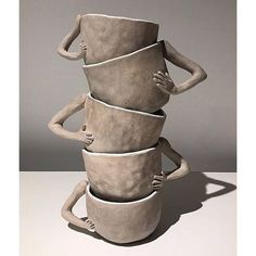 three clay sculptures stacked on top of each other with one holding the other's head