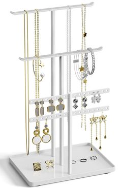 a white jewelry rack with several different types of earrings on the top and two rows of necklaces hanging from it