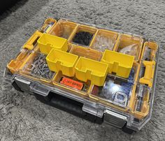 an open tool box on the floor with screws and other tools in it's tray