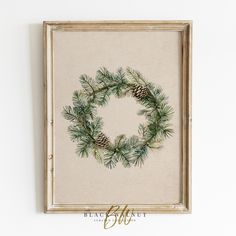 a pine cone wreath is hung on the wall above a framed canvas with gold lettering