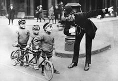 an old photo of a man riding a bike with three small children on the back