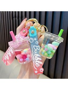 a person holding a plastic cup with candy in it and a keychain attached to it