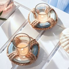 two glass cups and saucers with rope wrapped around them sitting on a white table