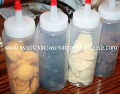 four plastic containers filled with food sitting on top of a wooden table next to each other