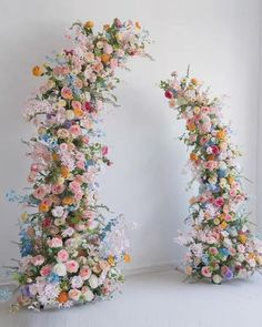 two archways made out of flowers on the floor in front of a white wall