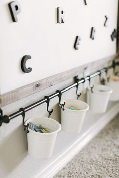 three buckets are hanging on the wall with letters and numbers attached to each one