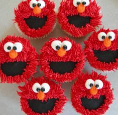 cupcakes with red frosting and black icing decorated to look like sesame street characters