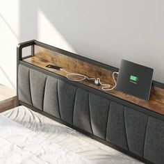 a laptop is plugged into the side of a bed with a wooden headboard