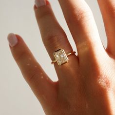 a woman's hand with a diamond ring on top of her finger and the other hand holding it