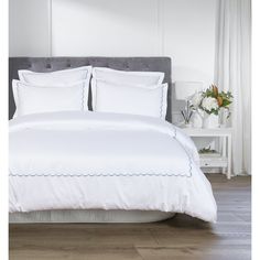 a bed with white sheets and pillows in a room