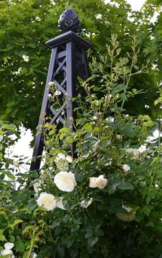 a black tower with white flowers in the foreground and green leaves on the other side