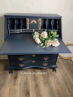 a blue desk with flowers on top and gold trim around the edges, in front of a white wall