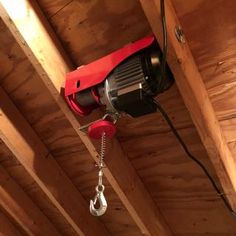 a red and black corded phone hanging from the ceiling in a room with wood paneling