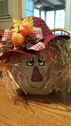 a scarecrow hat with hay and flowers on it sitting on top of a table