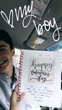 a man holding up a happy valentine's day card in the back of a car