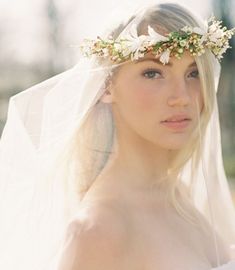 a woman wearing a veil and flowers in her hair is looking at the camera while standing outside