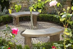 two stone benches sitting next to each other on a brick patio surrounded by greenery