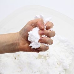 a hand is holding some white powder in front of a pile of rice on a plate