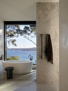 a bathroom with a large bathtub sitting next to a window overlooking the water and trees