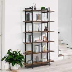 a bookshelf in the corner of a room with stairs and potted plant