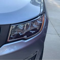 the front end of a gray car with bats on it's hood and headlight