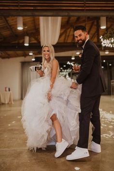 a man and woman dressed in wedding attire standing next to each other holding champagne flutes