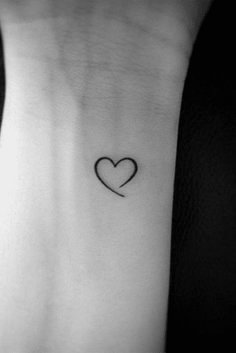 a small heart tattoo on the back of a woman's left arm and wrist