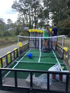 two people standing on a tennis court in the back of a truck