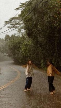 two people walking down the street in the rain with an umbrella over their head,