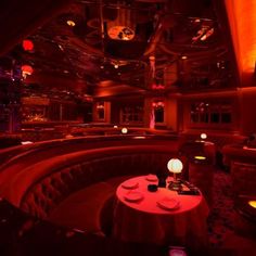 a dimly lit restaurant with round tables and red lights on the ceiling, along with seating