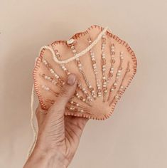 a hand holding an orange fan with pearls on it's side and the top half of its shell