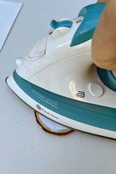 someone is using a steam iron to clean the surface of a white table with blue trim