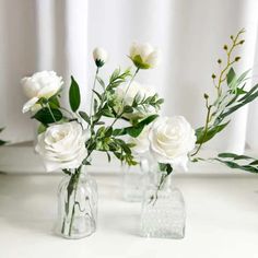 two clear vases with white flowers in them