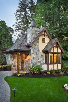 a small house with stone and wood accents in the front yard, surrounded by lush green grass