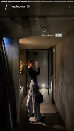 a woman taking a selfie with her cell phone in an empty hallway at night