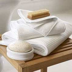 a pile of white towels sitting on top of a wooden table