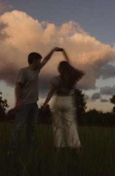 two people standing in the grass with their arms around each other as they hold hands