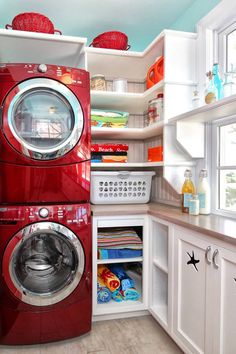 a red washer and dryer in a white kitchen with open shelve