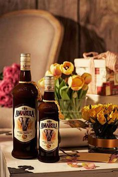 two bottles of beer sitting on top of a table next to flowers and other items