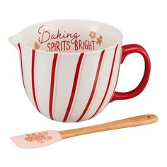 a red and white striped cup with a wooden spoon next to it on a white background