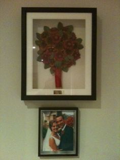 two framed pictures hang on the wall above a toilet with a red flower in it