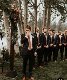 a group of young men standing next to each other in front of some tall trees