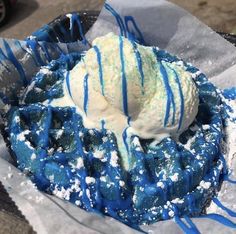 a waffle topped with blue and white icing on top of aluminum foil covered in powdered sugar