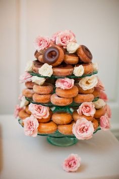 donuts are stacked on top of each other with pink flowers and roses around them