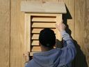 a person standing in front of a wooden door opening to a small window with shutters