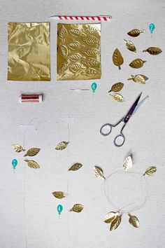 gold foil leaves, scissors and tape are on the table next to some other items