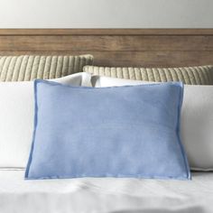 a blue pillow sitting on top of a white bed