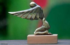 a bronze statue of a bird on a wooden base