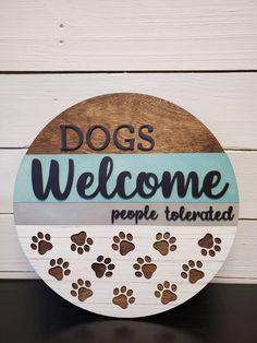 a wooden sign that says dogs welcome people to the area with paw prints on it